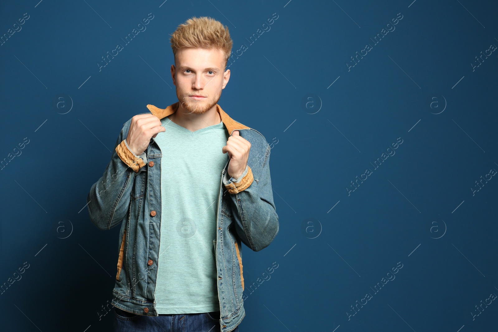 Photo of Young man wearing blank t-shirt on blue background. Mockup for design