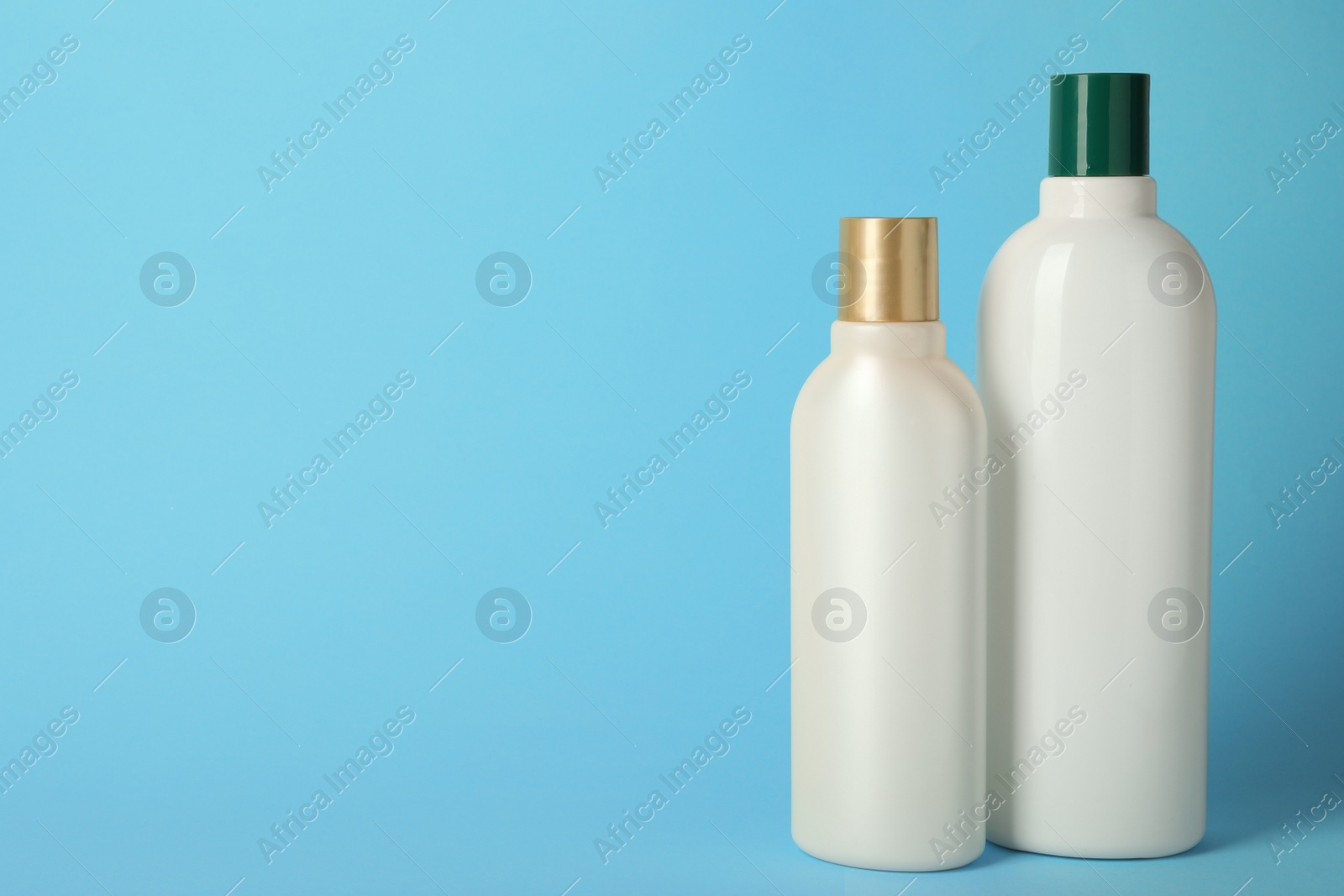 Photo of Bottles with hair care cosmetics on light blue background