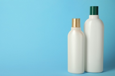 Bottles with hair care cosmetics on light blue background