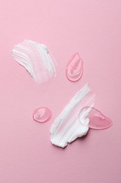 Photo of Samples of cosmetic gel and cream on pink background, top view