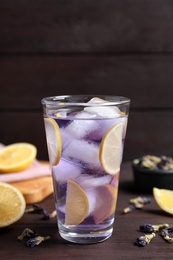Photo of Organic blue Anchan with lemon in glass on wooden table. Herbal tea