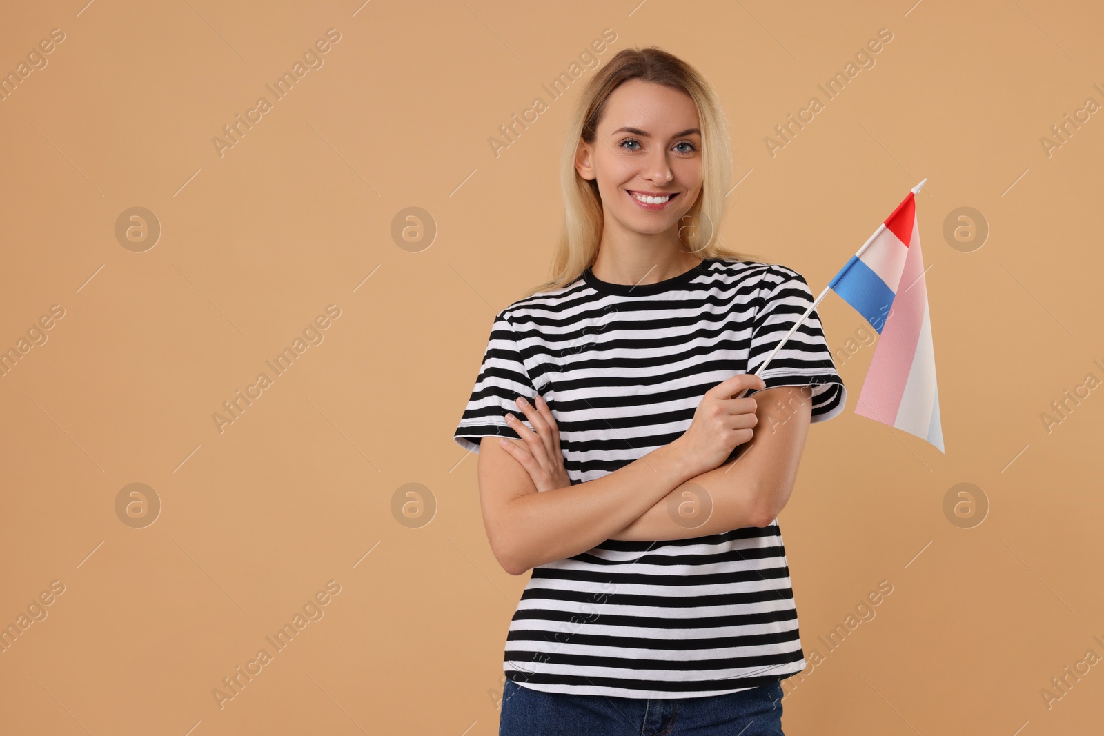 Photo of Happy woman with flag of Netherlands on beige background, space for text