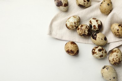 Photo of Many speckled quail eggs on white marble table, flat lay. Space for text