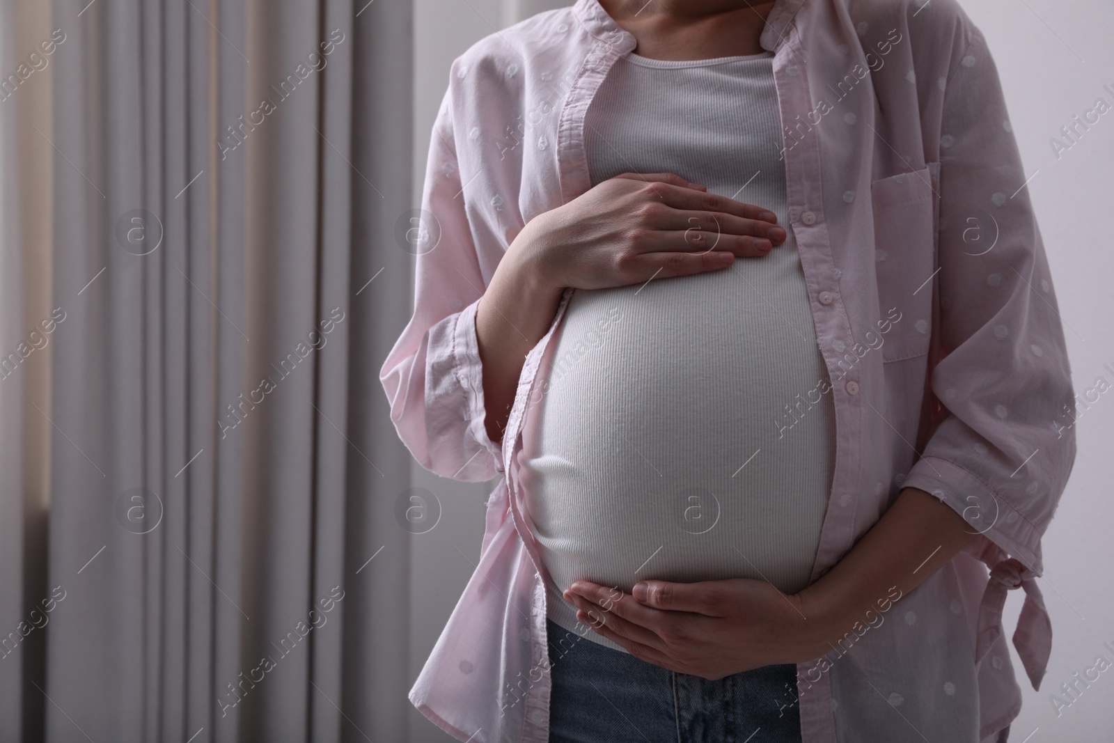 Photo of Young pregnant woman at home, closeup view. Space for text