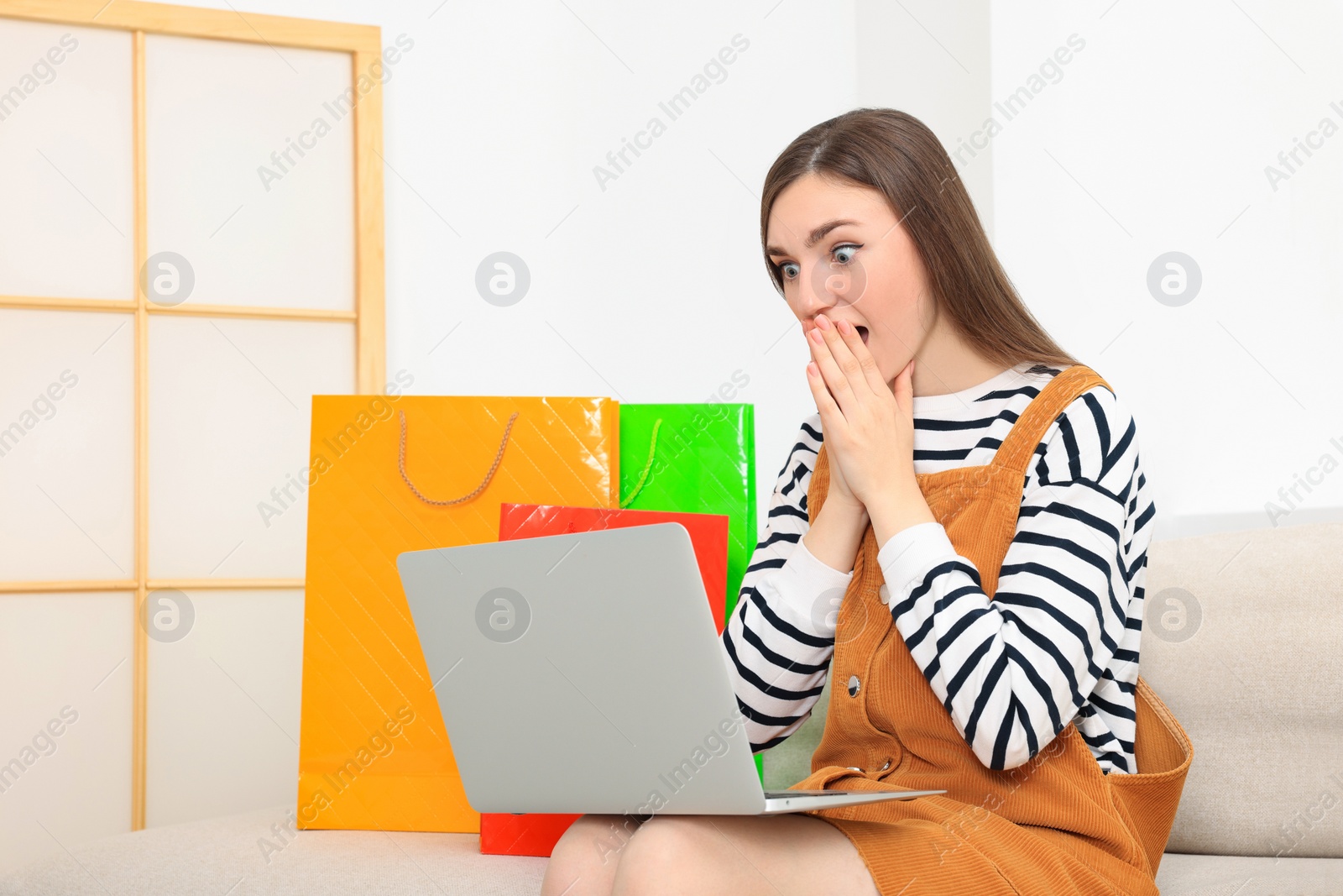 Photo of Special Promotion. Emotional woman looking at laptop on sofa indoors, space for text