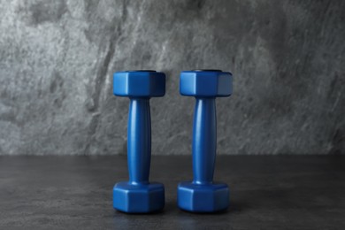 Photo of Blue vinyl dumbbells on table against grey background