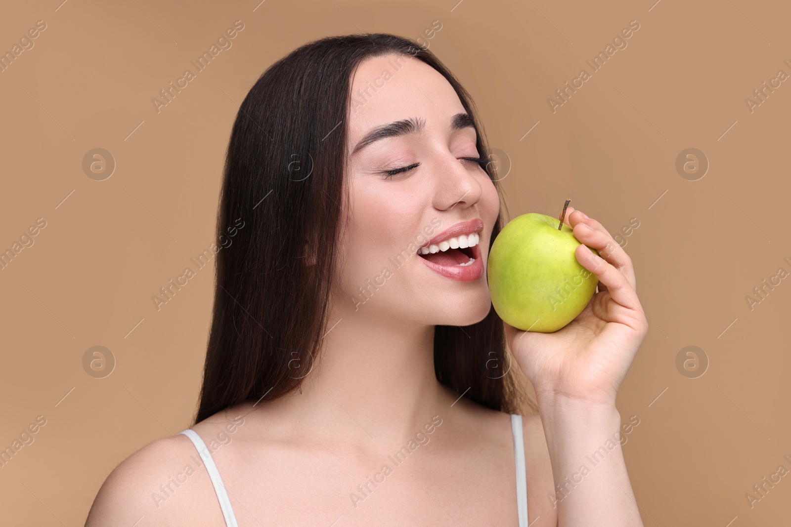 Photo of Beautiful young woman with apple on beige background