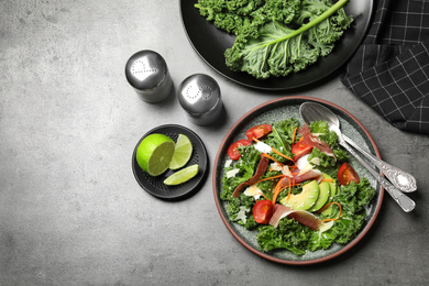 Photo of Delicious kale salad with prosciutto served on grey table, flat lay