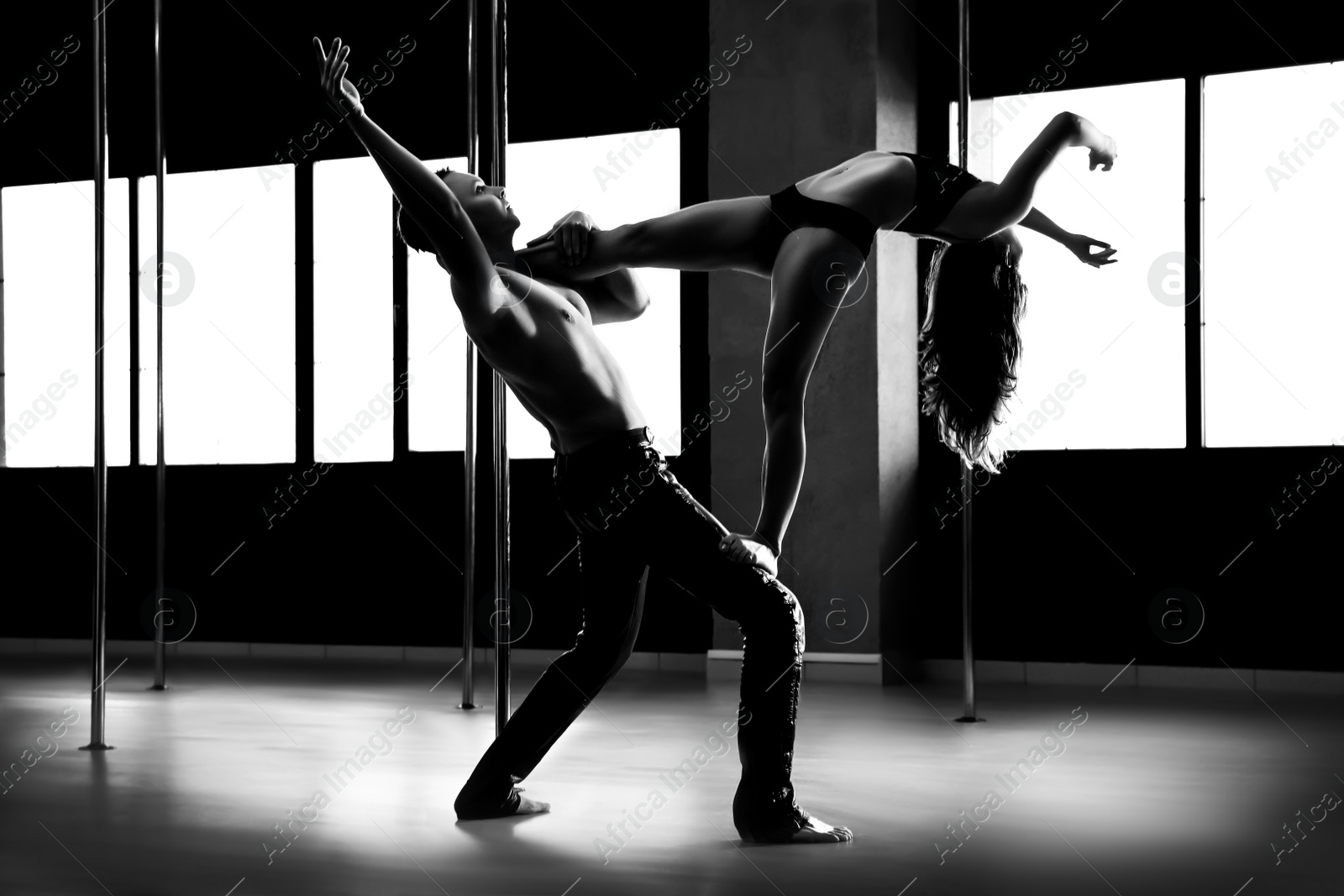 Image of Young couple dancing in studio with poles