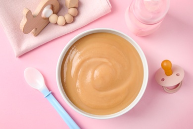 Flat lay composition with bowl of healthy baby food on pink background