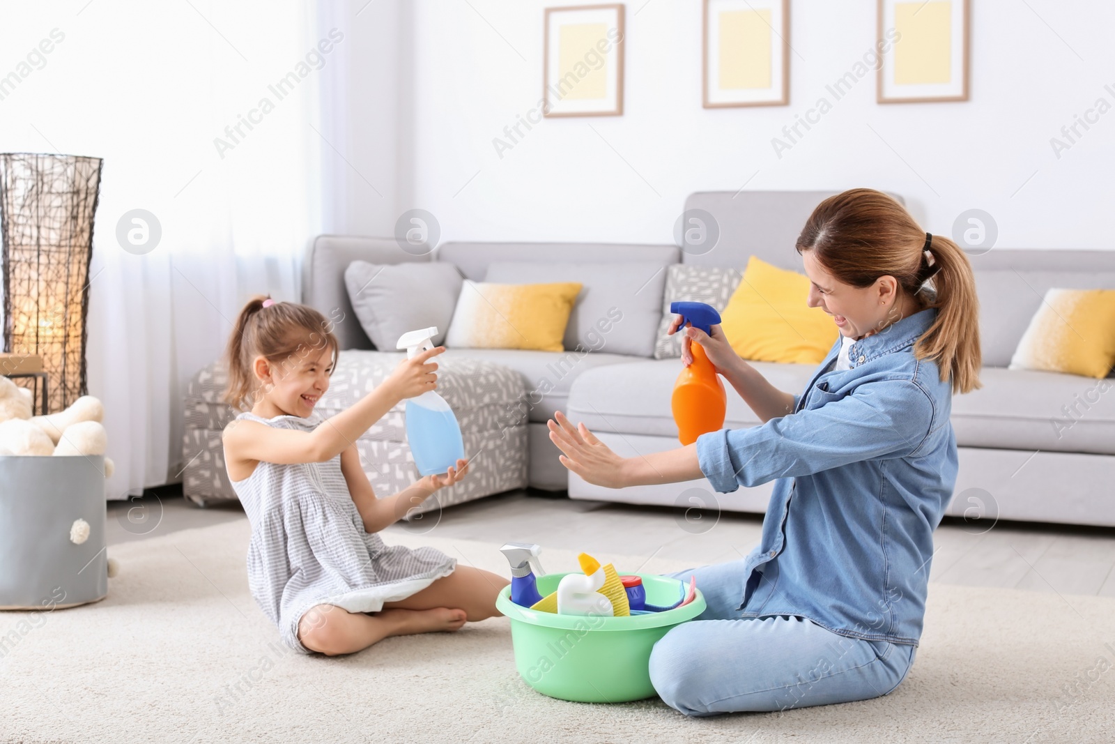 Photo of Housewife and daughter having fun while cleaning home