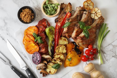 Photo of Delicious grilled meat and vegetables served on white marble table, flat lay