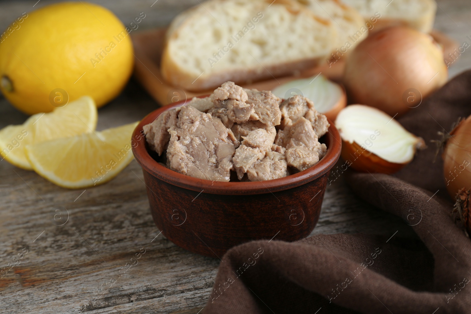 Photo of Bowl of tasty cod liver on wooden table, closeup