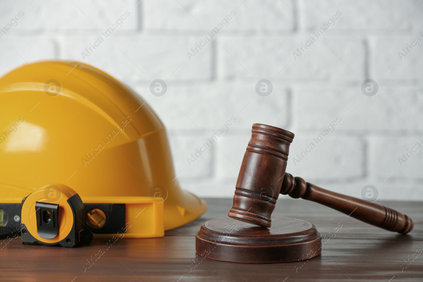 Photo of Construction and land law concepts. Judge gavel, protective helmet, level with tape measure on wooden table, space for text