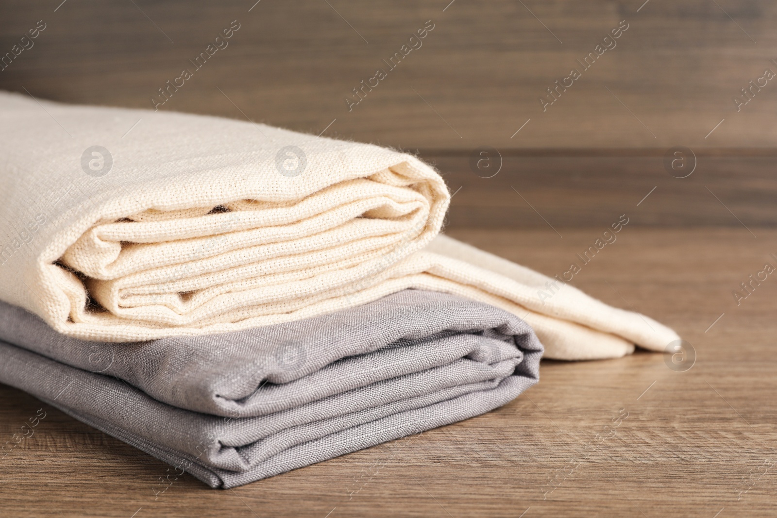 Photo of Folded hemp cloths on wooden table, closeup. Space for text