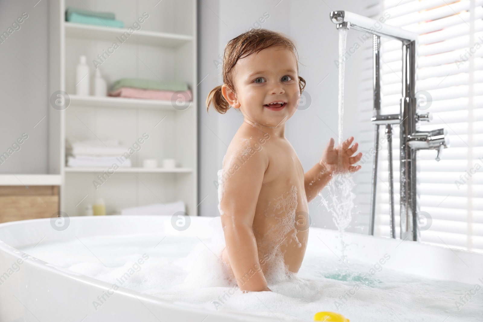 Photo of Cute little girl in foamy bath at home