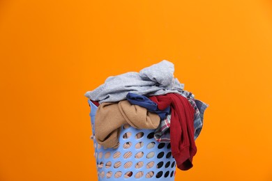 Photo of Laundry basket with clothes against orange background