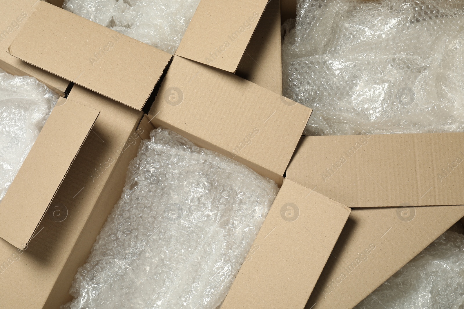 Photo of Many open cardboard boxes with bubble wrap as background, top view