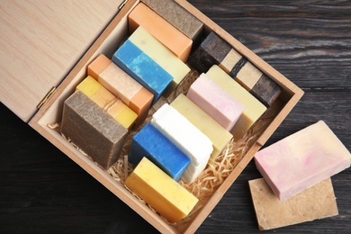 Photo of Many different handmade soap bars in wooden box on table, top view