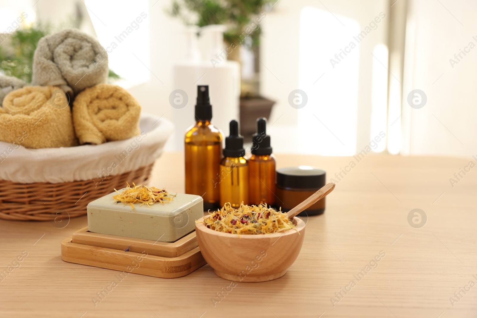 Photo of Soap bar, dry flowers, bottles of essential oils, jar with cream and towels on wooden table indoors, space for text. Spa time