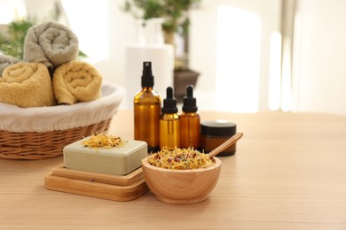 Photo of Soap bar, dry flowers, bottles of essential oils, jar with cream and towels on wooden table indoors, space for text. Spa time