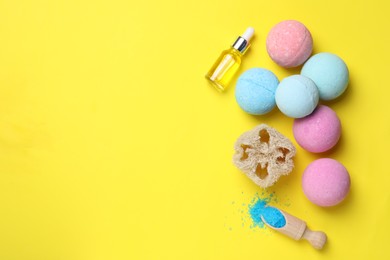 Bath bombs, loofah sponge, bottle and sea salt on yellow background, flat lay. Space for text