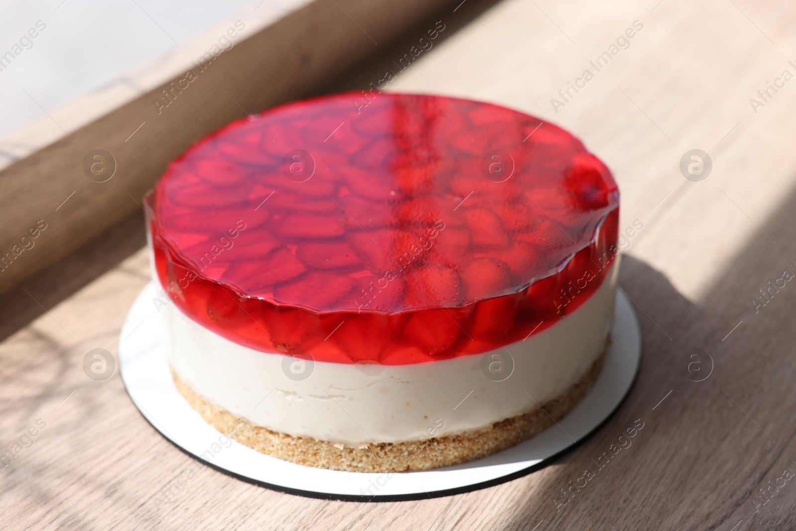 Photo of Delicious cheesecake with jelly and strawberries on wooden table, closeup