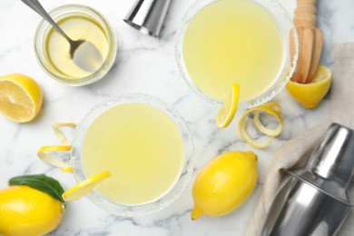 Photo of Delicious bee's knees cocktails and ingredients on white marble table, flat lay