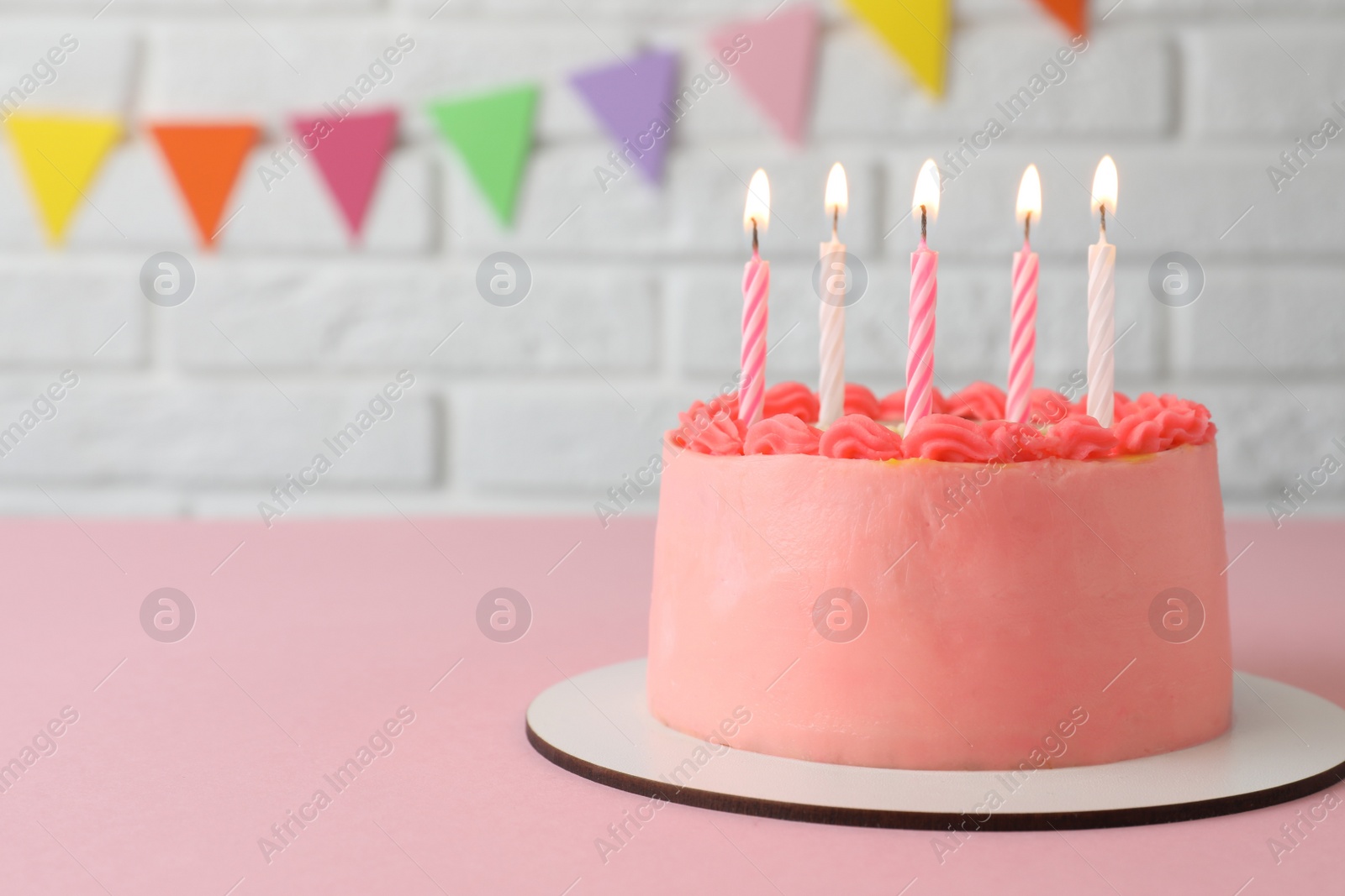 Photo of Cute bento cake with tasty cream and burning candles on pink table. Space for text