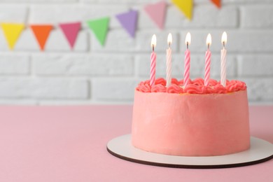 Cute bento cake with tasty cream and burning candles on pink table. Space for text