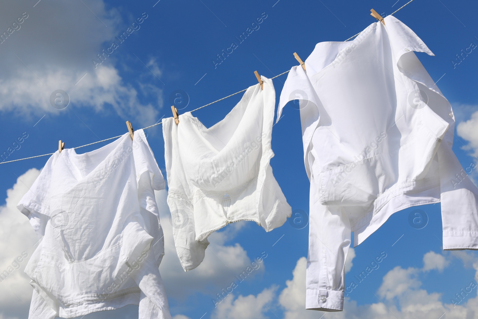 Photo of Clean clothes hanging on washing line against sky. Drying laundry