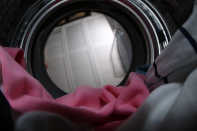 Clothes in washing machine indoors, view from inside. Laundry day