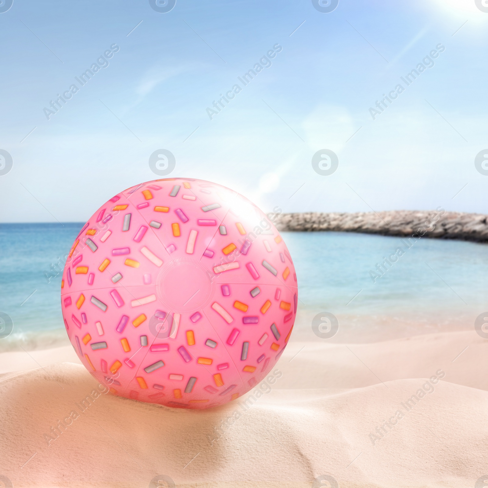 Image of Pink beach ball on sandy coast near sea