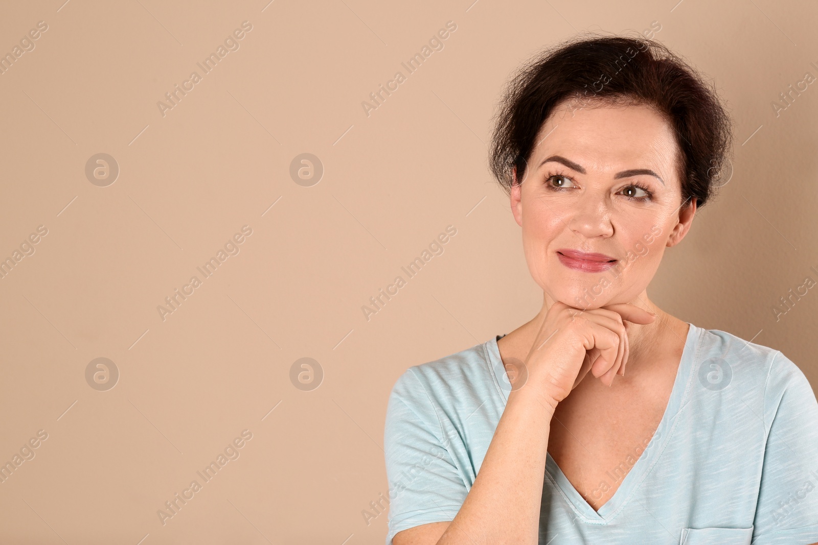 Photo of Portrait of charming mature woman with healthy beautiful face skin and natural makeup on beige background, space for text