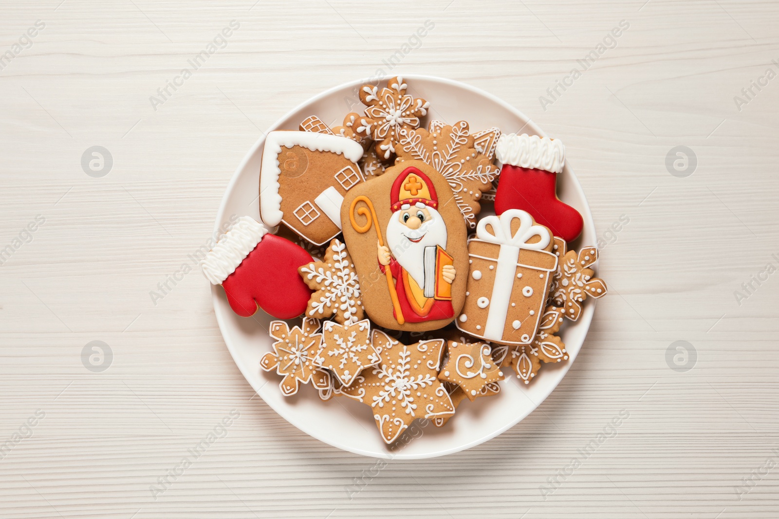 Photo of Tasty gingerbread cookies on white wooden table, top view. St. Nicholas Day celebration