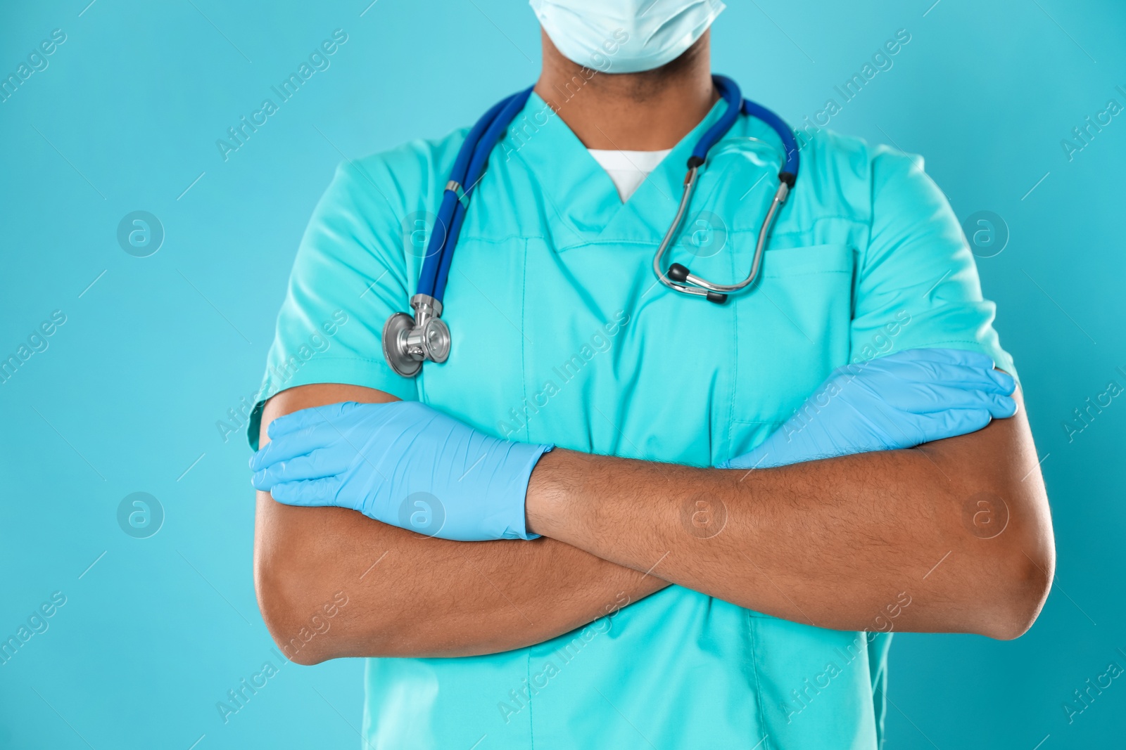 Photo of Doctor or medical assistant (male nurse) in uniform with stethoscope on turquoise background, closeup