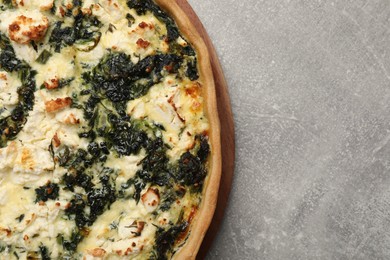 Photo of Delicious homemade spinach quiche on light gray table, top view. Space for text