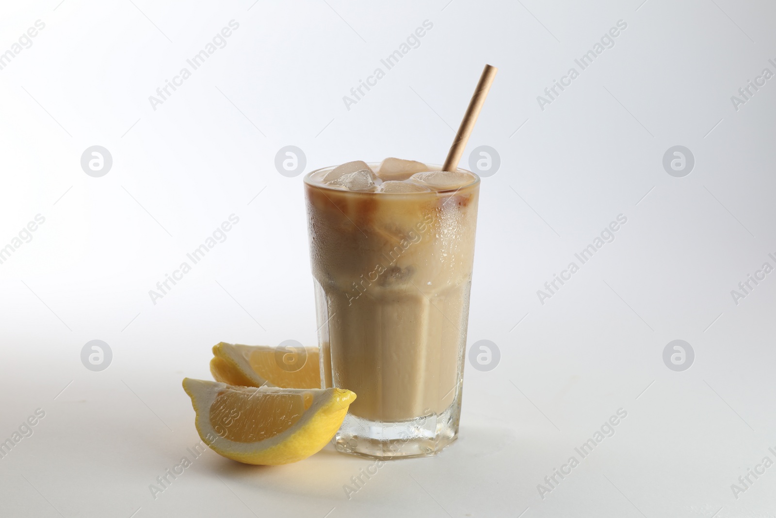 Photo of Iced coffee with milk in glass and cut lemon on white background