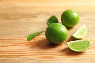 Photo of Fresh ripe limes on wooden table. Citrus fruit