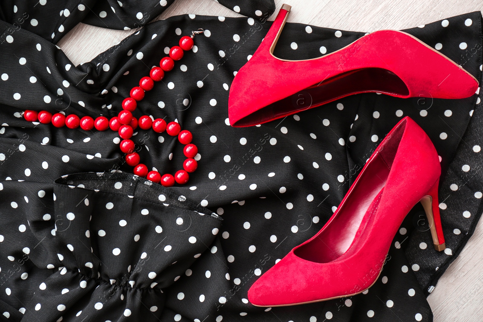 Photo of Elegant female shoes, dress and necklace on wooden floor