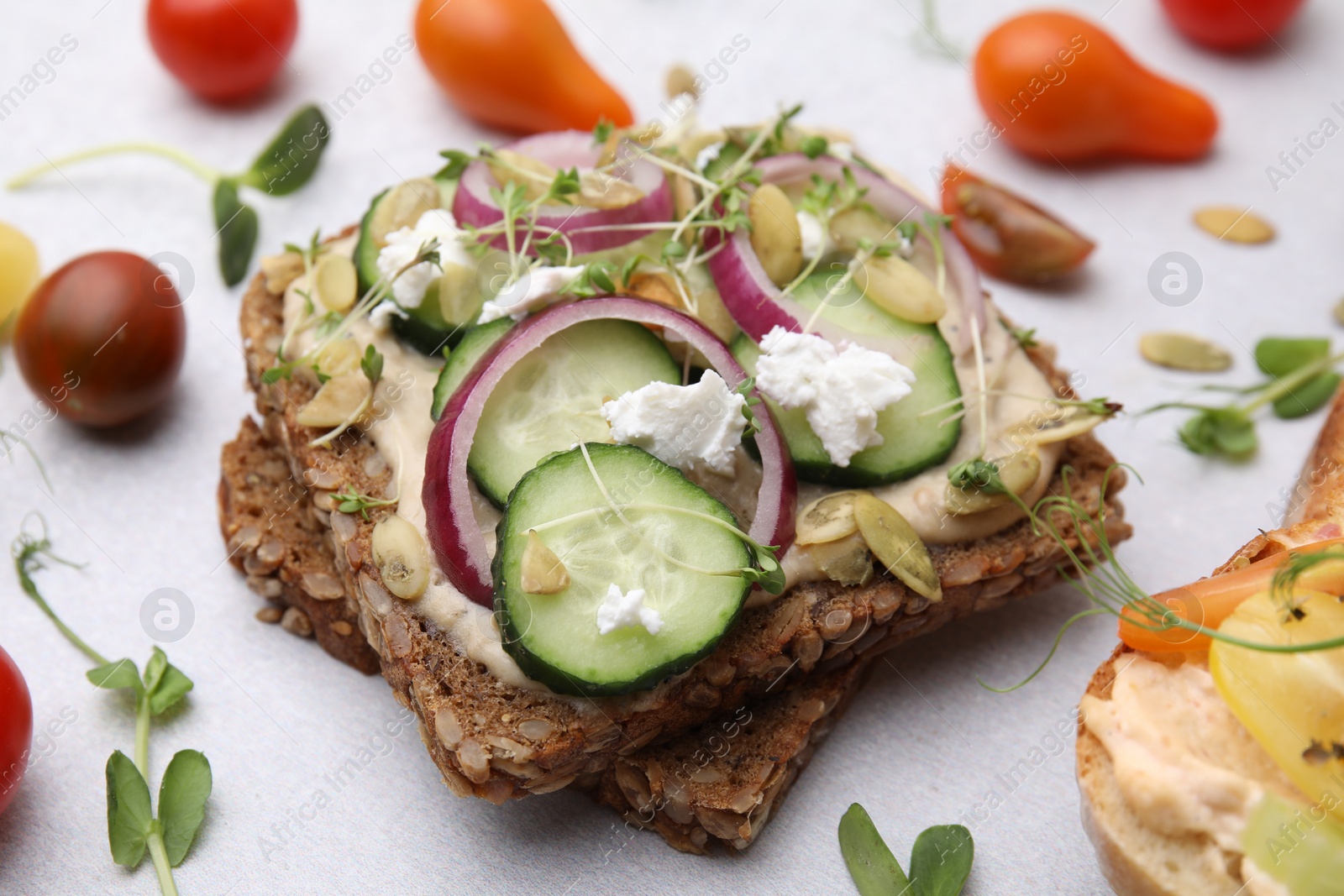 Photo of Tasty vegan sandwiches with vegetables on light grey table, closeup