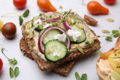 Tasty vegan sandwiches with vegetables on light grey table, closeup