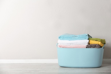 Photo of Basket with clean laundry on floor near color wall, space for text