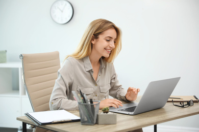 Photo of Pretty young woman working with laptop in office