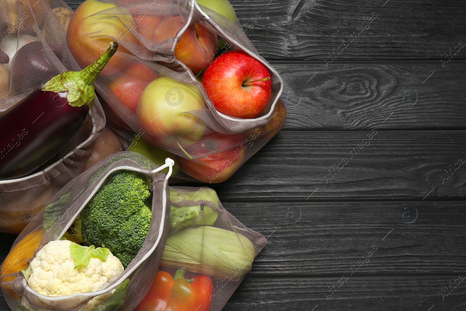 Photo of Different fresh vegetables in bags on wooden table, top view with space for text. Farmer harvesting