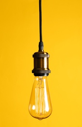 Hanging modern lamp bulb against yellow background