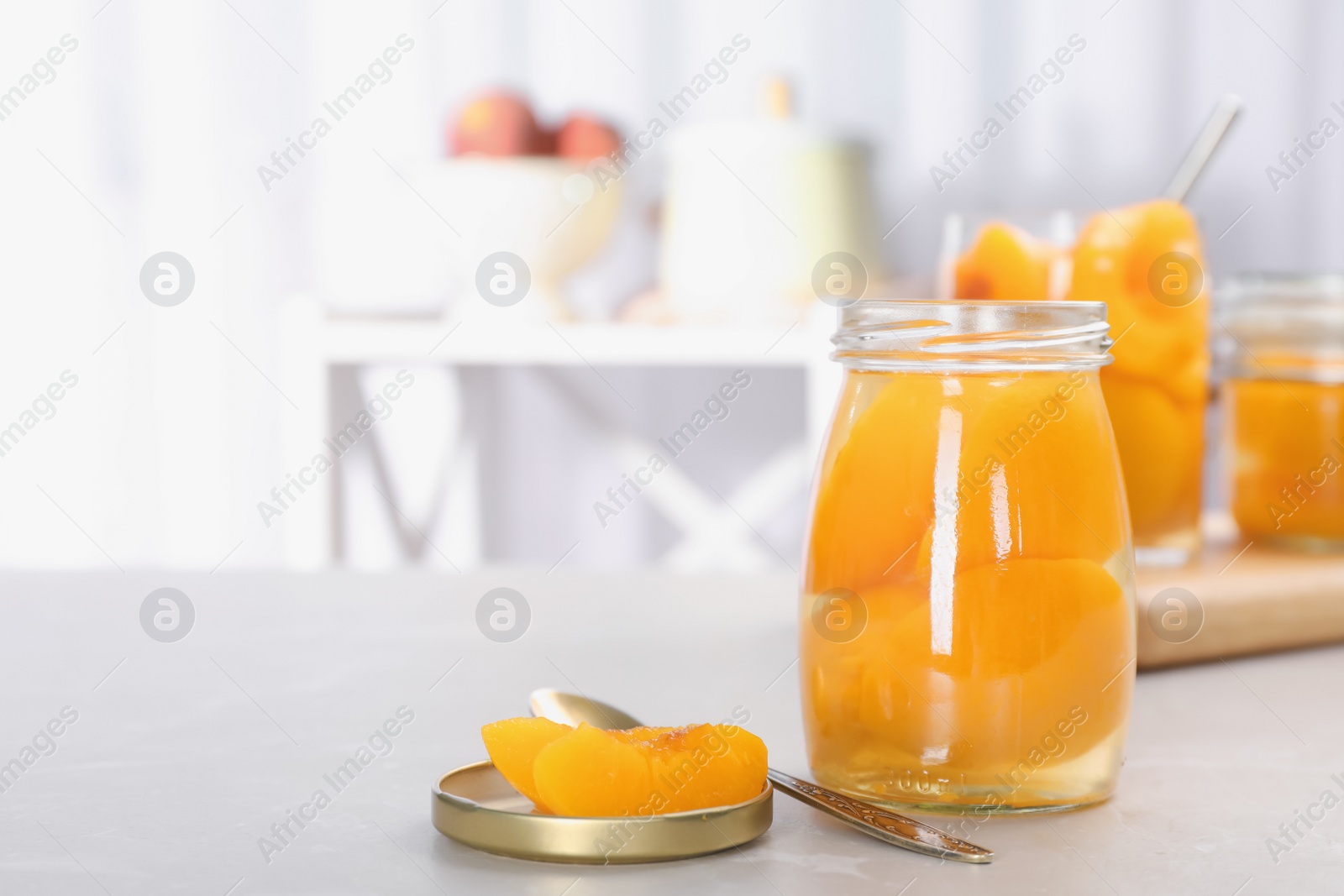 Photo of Glass jar with conserved peach halves on table. Space for text