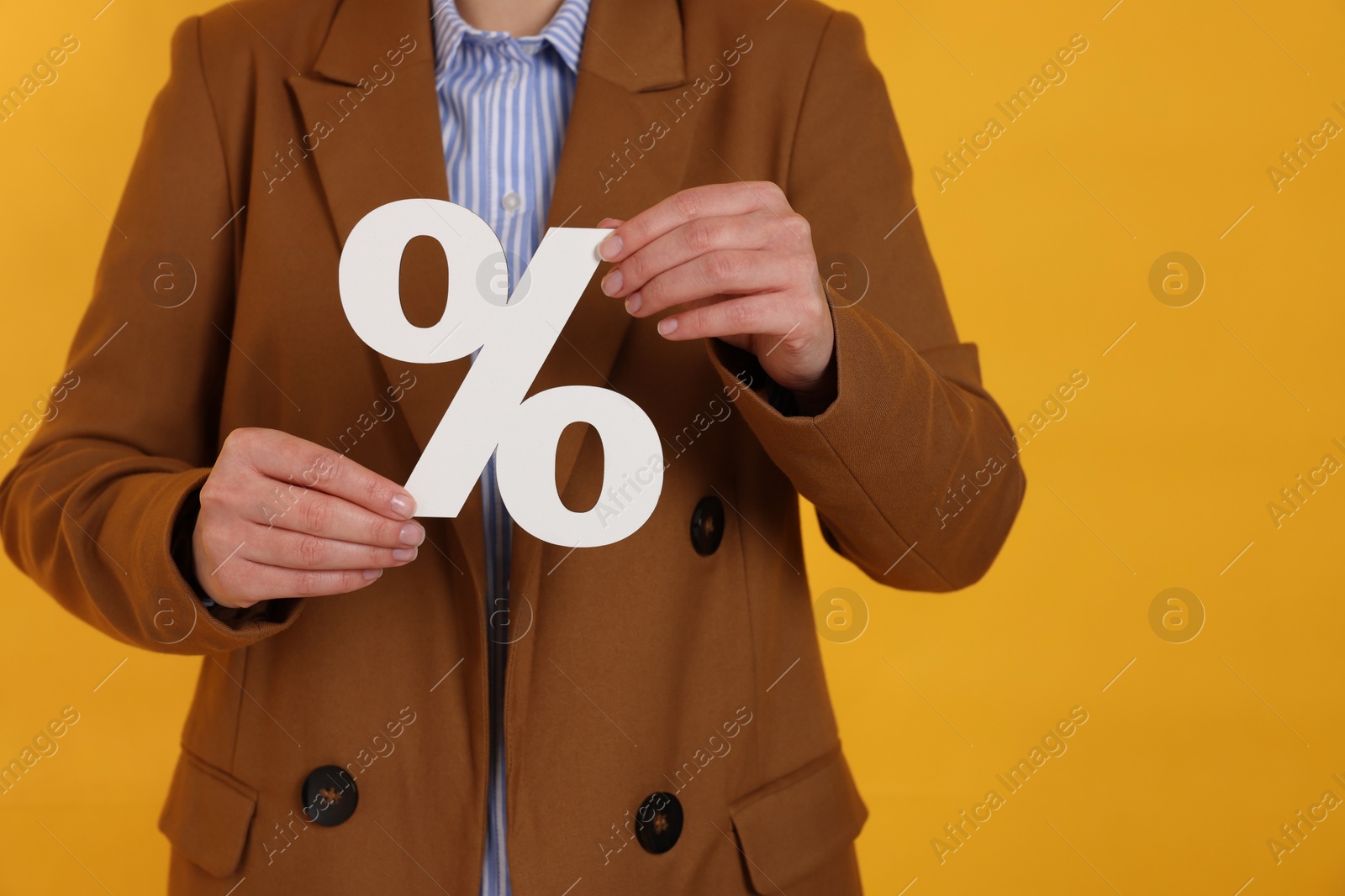 Photo of Woman holding percent sign on orange background, closeup