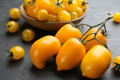 Photo of Ripe yellow tomatoes on black table, closeup