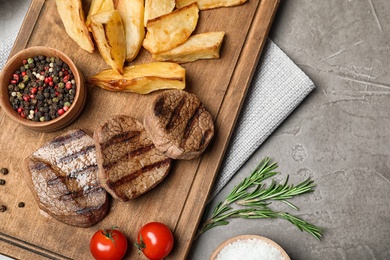 Photo of Grilled meat served with garnish on grey background, flat lay. Space for text
